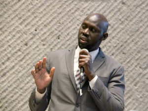 Councilor Dr. Chol Majok gives a speech during Finding Common Ground about how refugees and displaced people are always refugees in their hearts and how important it is to become an ally.