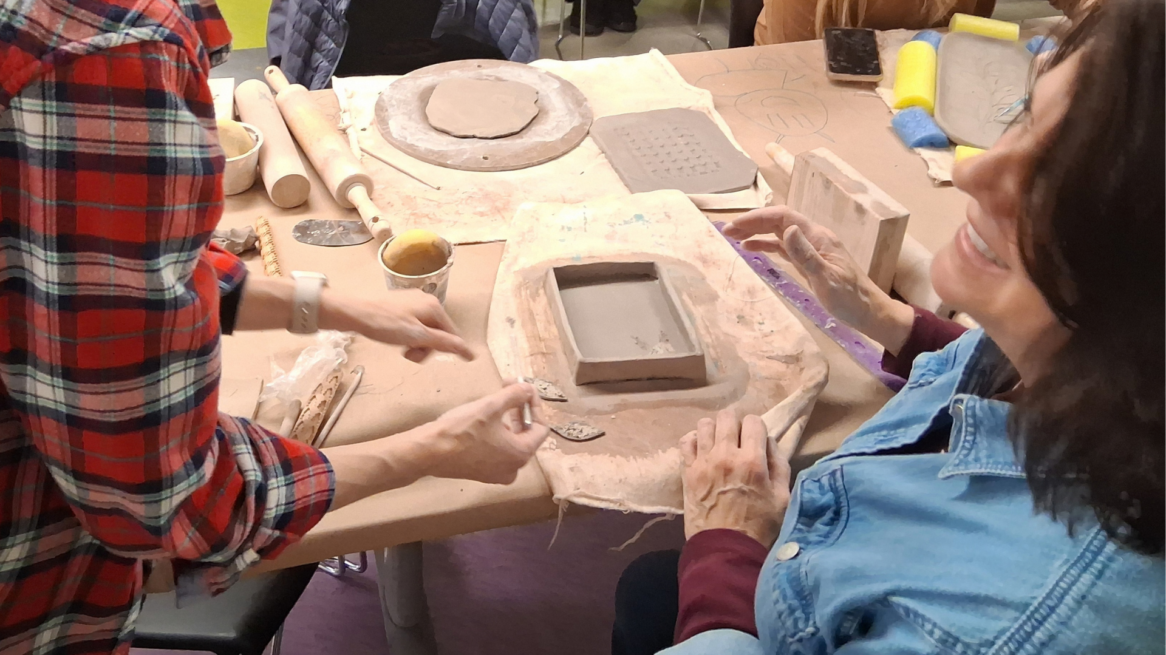 instructor and student work together during ceramics workshop.