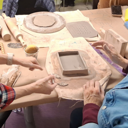 instructor and student work together during ceramics workshop.