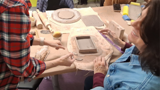 instructor and student work together during ceramics workshop.
